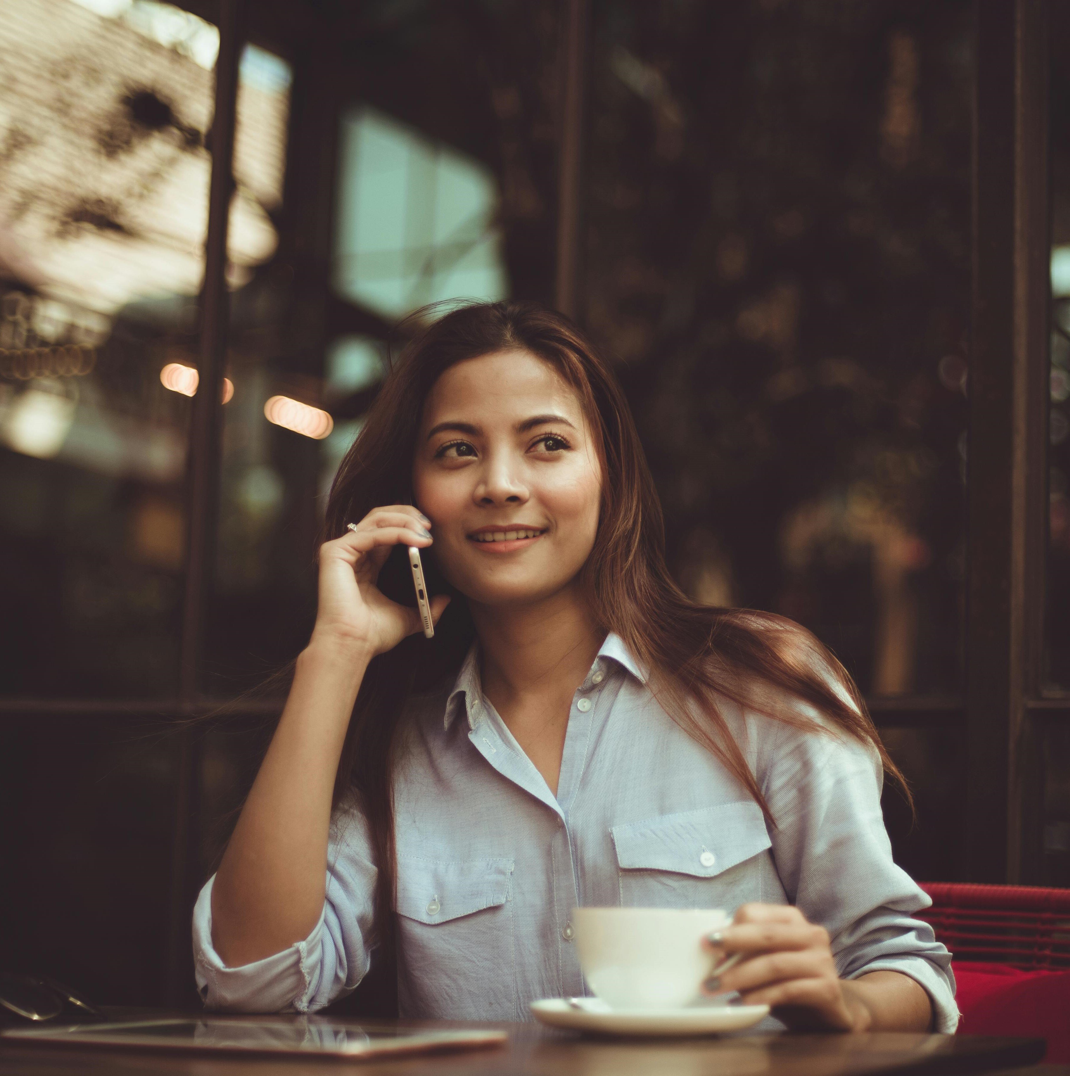 chica hablando por telefono sentada en una mesa al aire libre